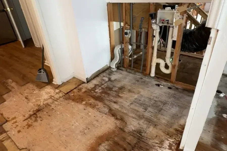 A wall opened around the plumbing with the wet flooring pulled up