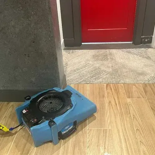 Water damage restoration in Spring Lake Park: an air mover at work drying a room after a leak
